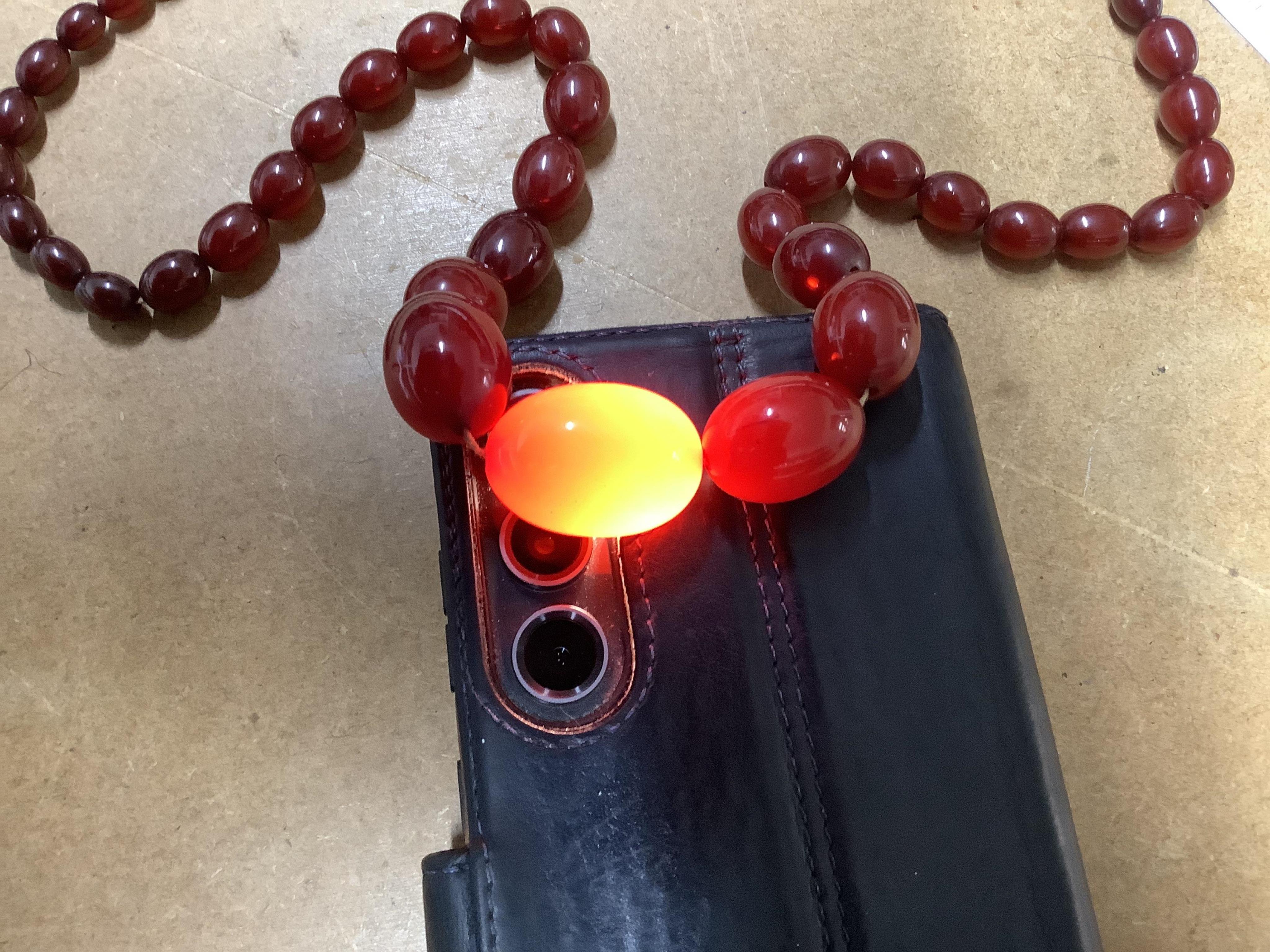 A cherry-coloured bakelite simulant amber necklace, composed of graduated beads measuring approximately 8-28mm, length 86cm, gross weight approximately 61 grams